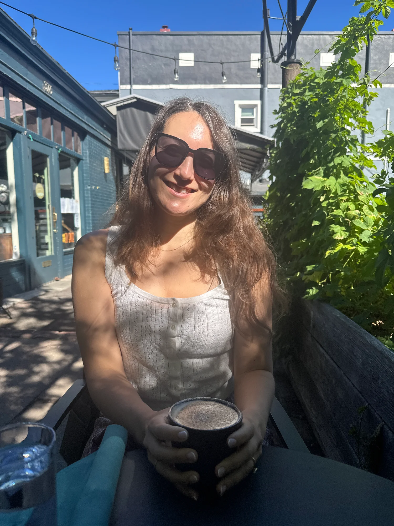 Amy Suto on the sunny back patio at Zi Spice in Ashland, Oregon, holding an A2 milk chai