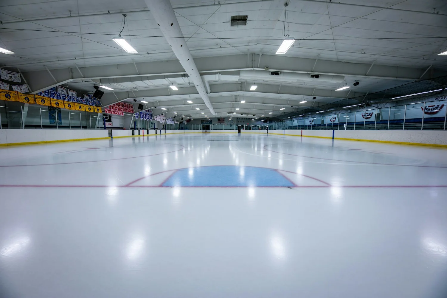 An empty indoor ice rink under bright lights, the setting every hockey romance book shares