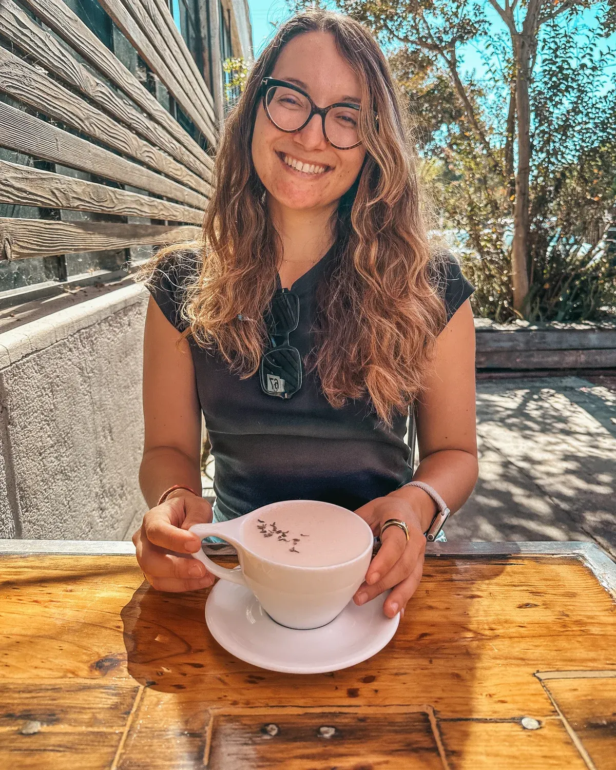 Amy Suto smiling at a sunny patio table with a very large latte