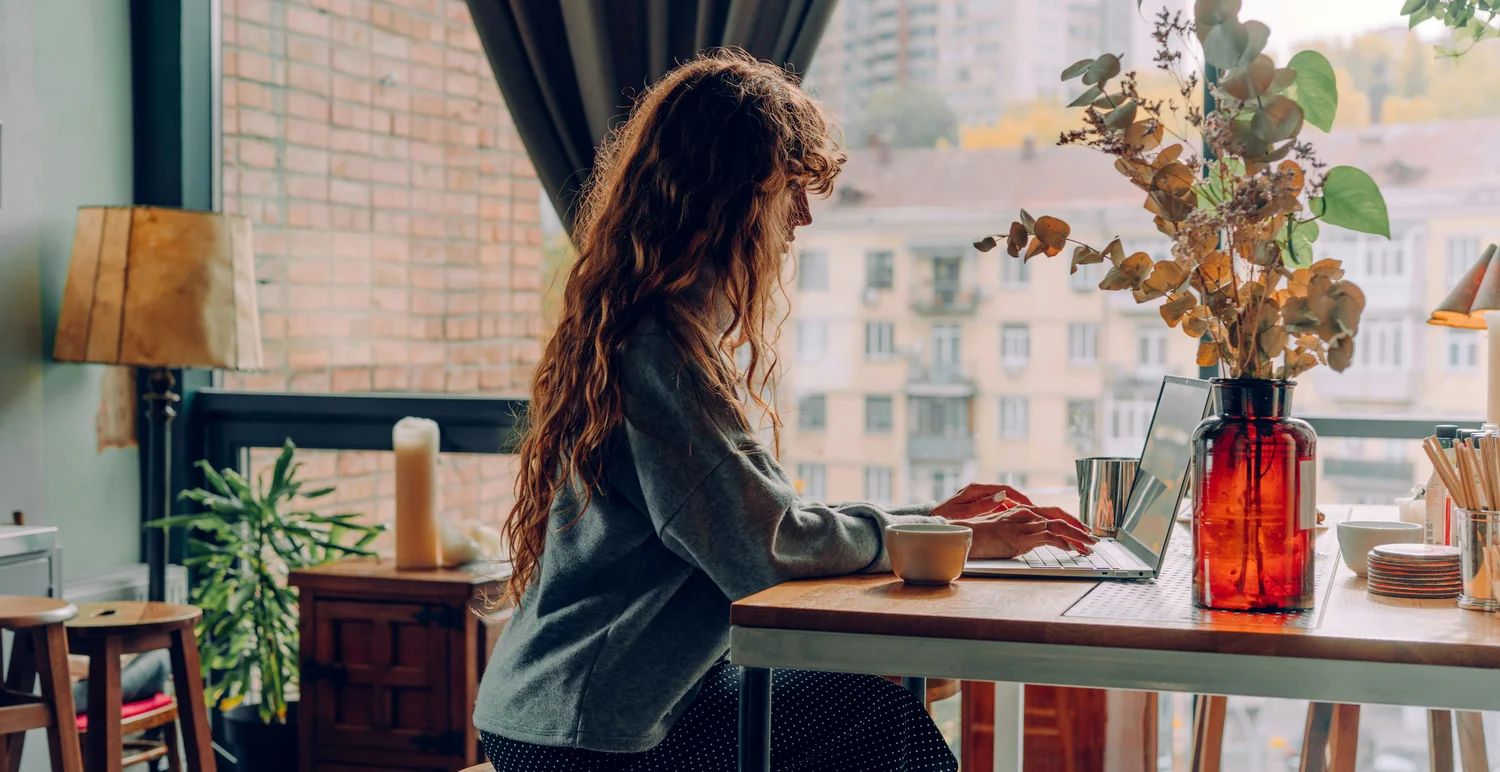 A writer reading at a laptop in a sunny cafe window