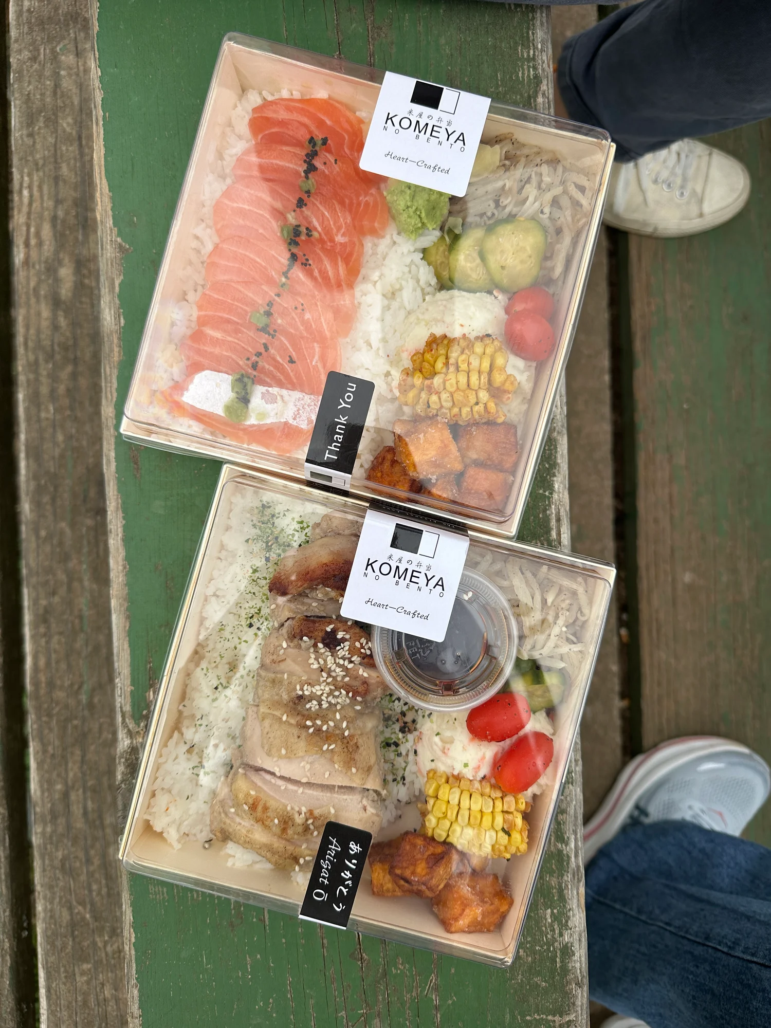 Komeya no Bento Salmon in Truffle Soy and Chicken Chashu bento boxes on a green picnic table