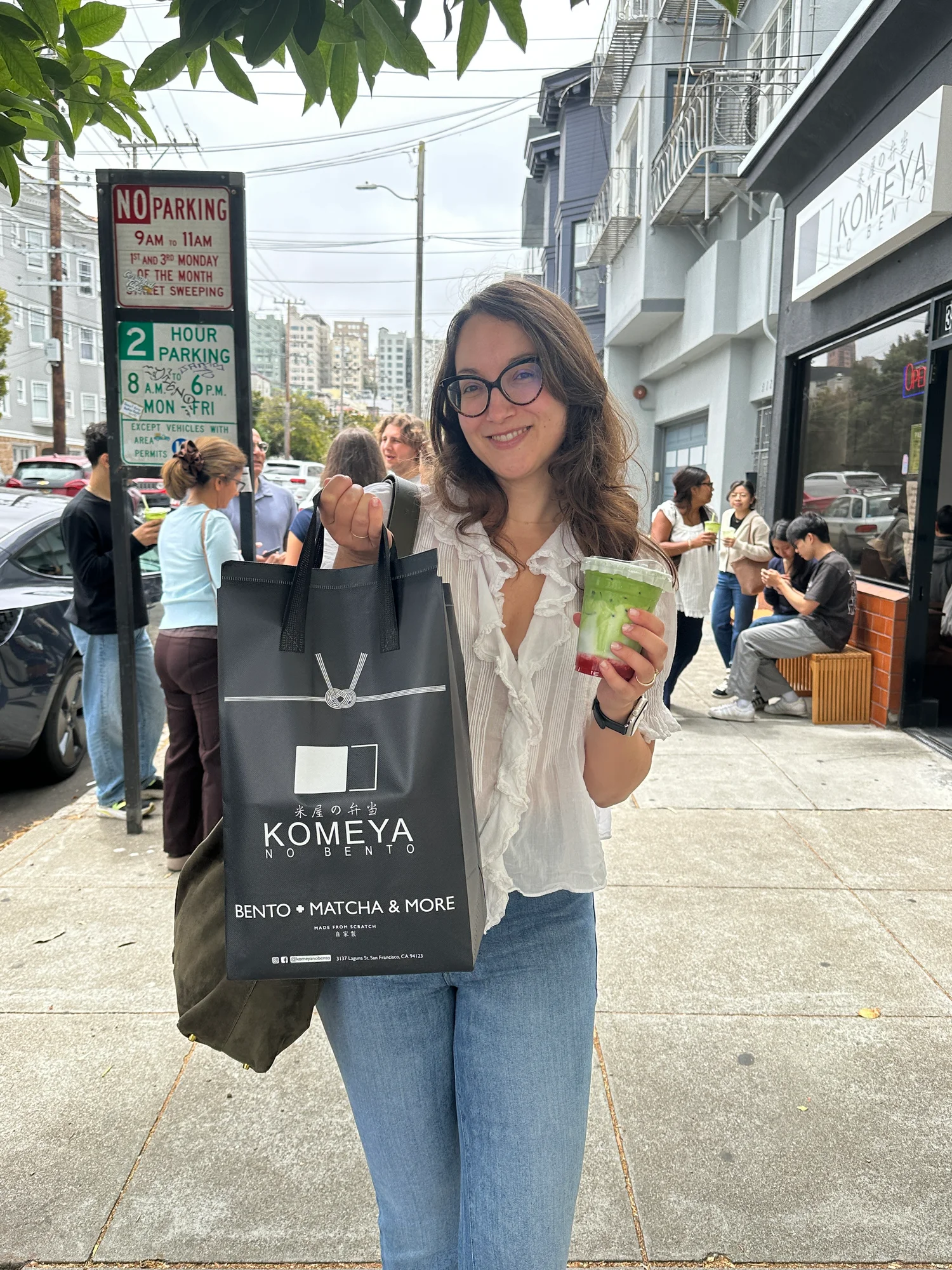 Amy Suto holding a Komeya no Bento bag and strawberry matcha outside the shop on Laguna Street in San Francisco