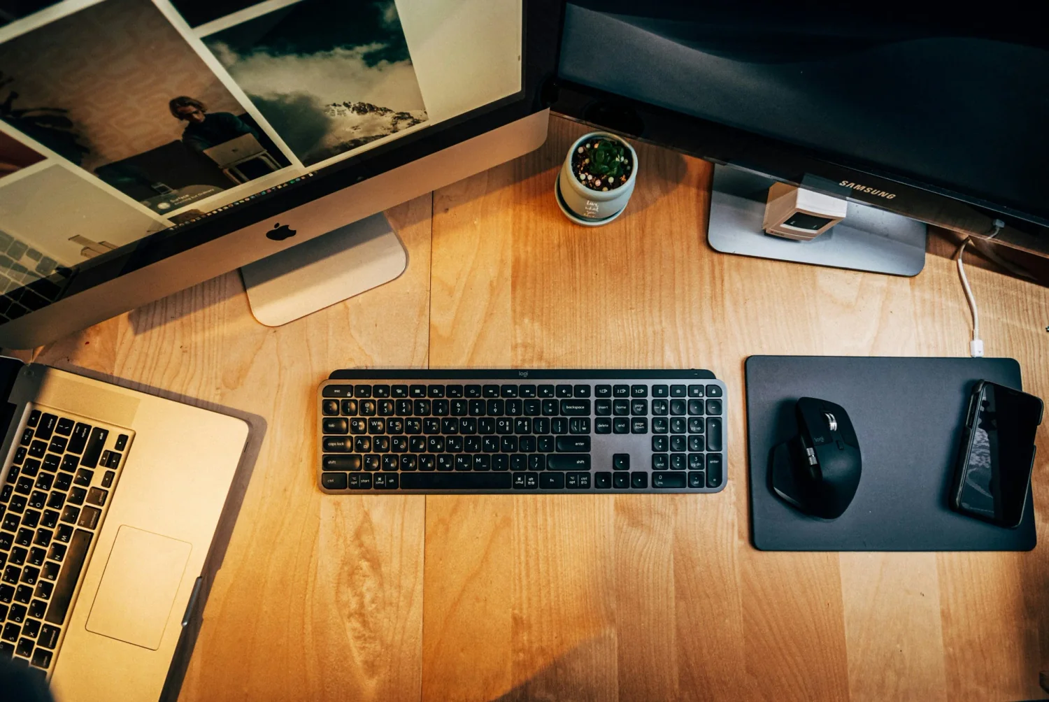 Modern remote work setup with multiple monitors, keyboard, and smartphone on a wooden desk — ideal for freelance writer professionals.