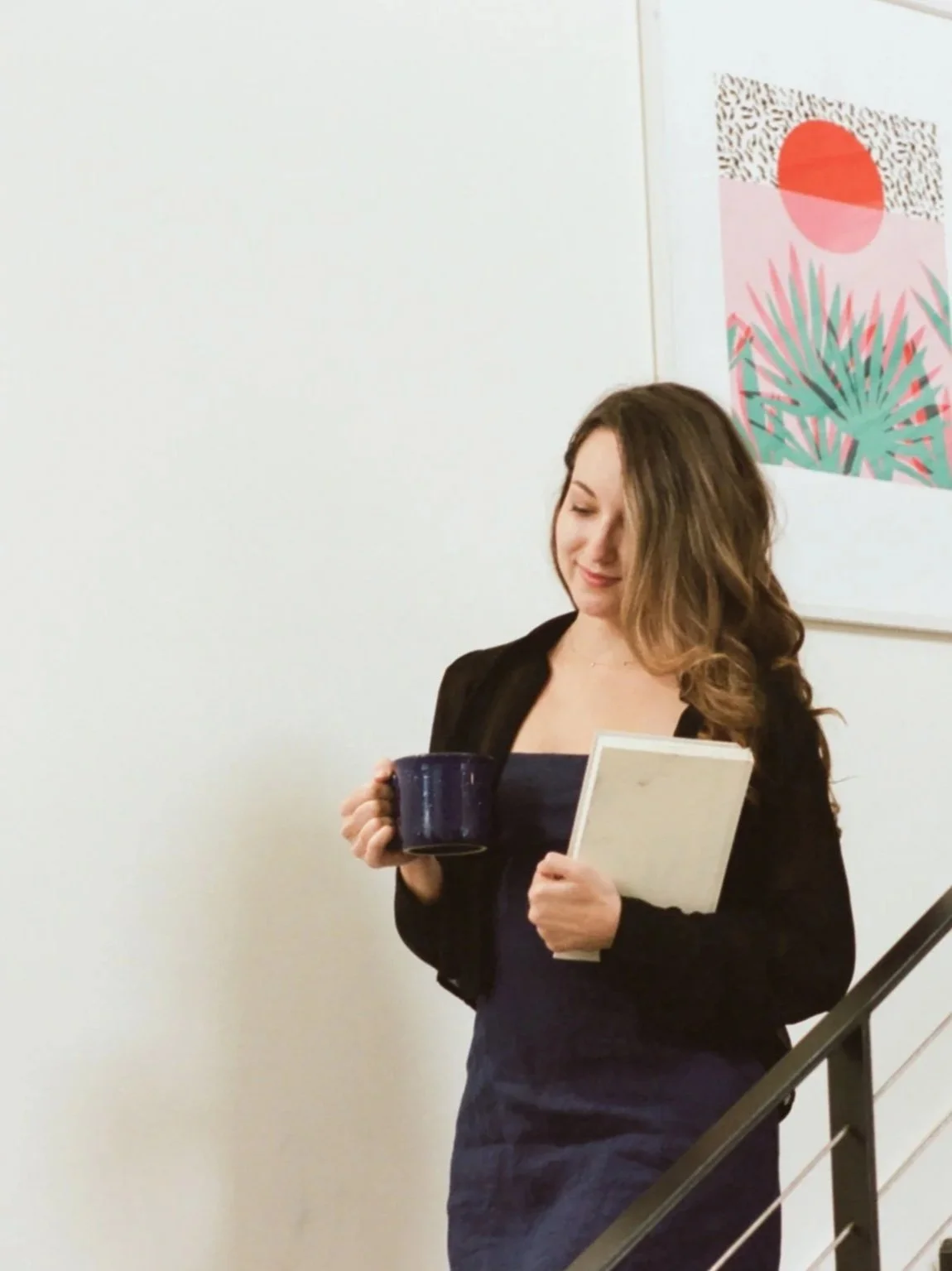 Woman walking down the stairs  holding coffee and a book