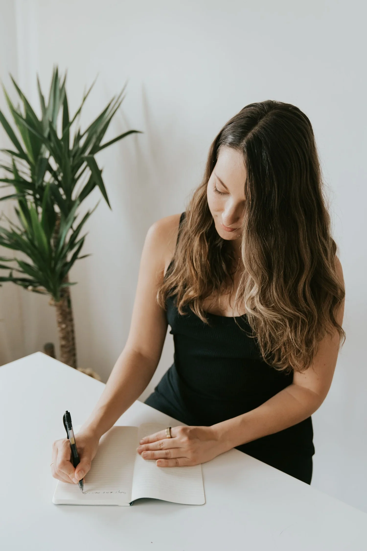 Amy Suto writing in a notebook, illustrating the intentional and strategic approach to freelance writing featured in her Six-Figure Freelance Writer guide and Writing Job Board.”