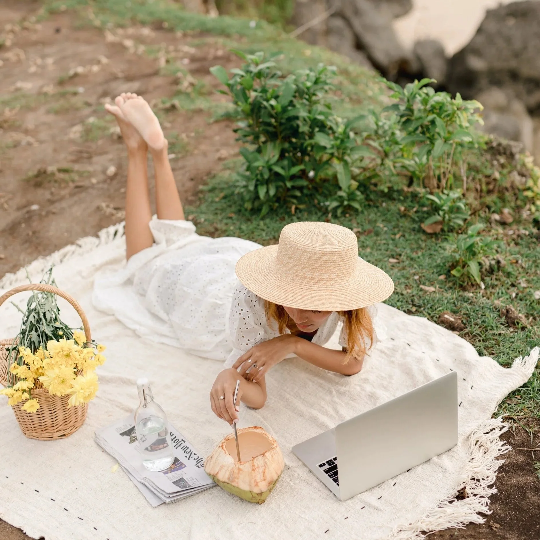 Writer relaxing in front of her laptop on a picnic blanket