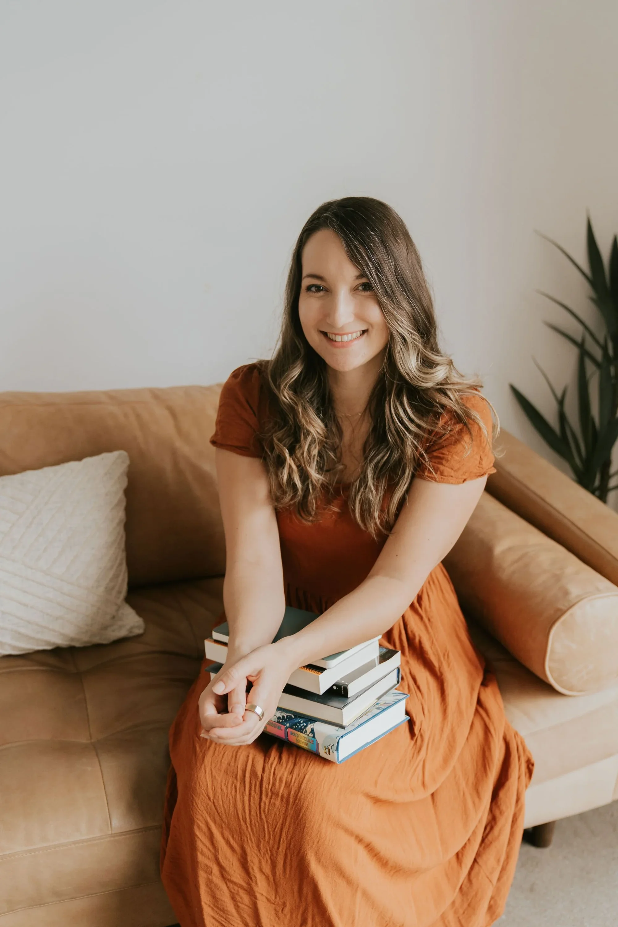 Amy Suto holding a stack of books ready to help ghostwriter your memoir