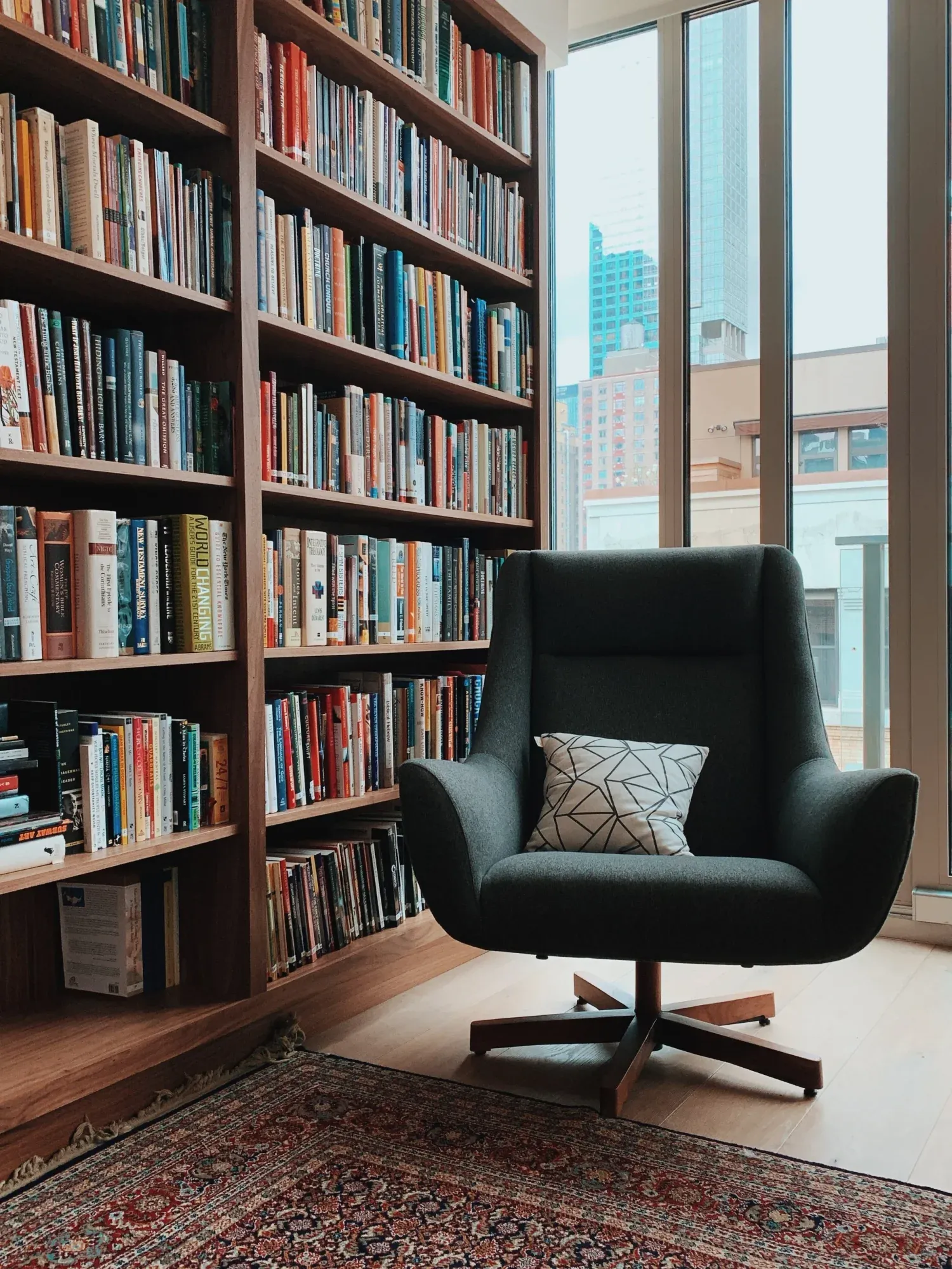 Cozy reading chair in a library filled with books, symbolizing the structured process of outlining a memoir or nonfiction book with guidance from Amy Suto.