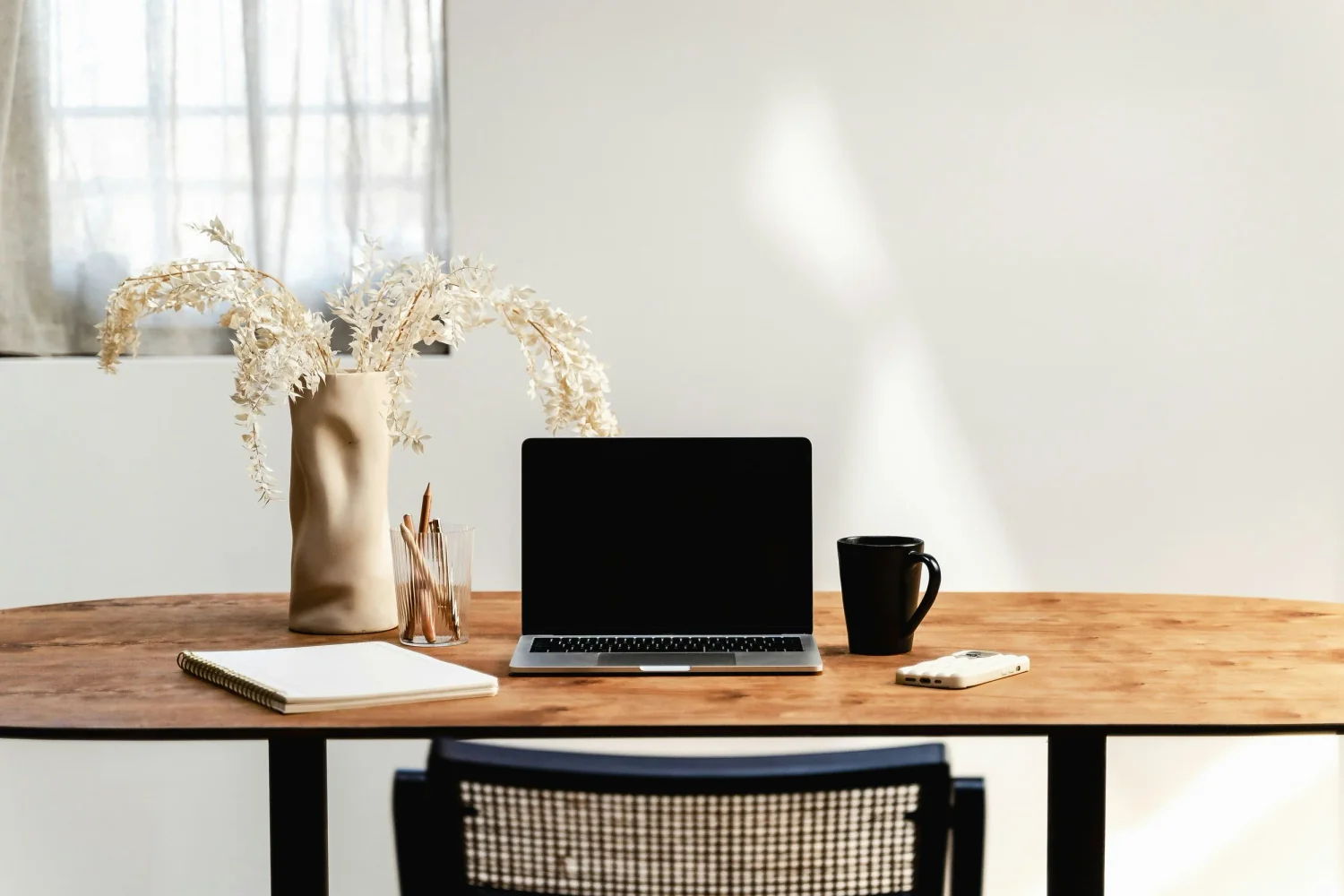 Minimalist workspace with a laptop, notebook, and coffee cup, representing the focus and structure needed to calculate a profitable hourly rate as a freelance writer.