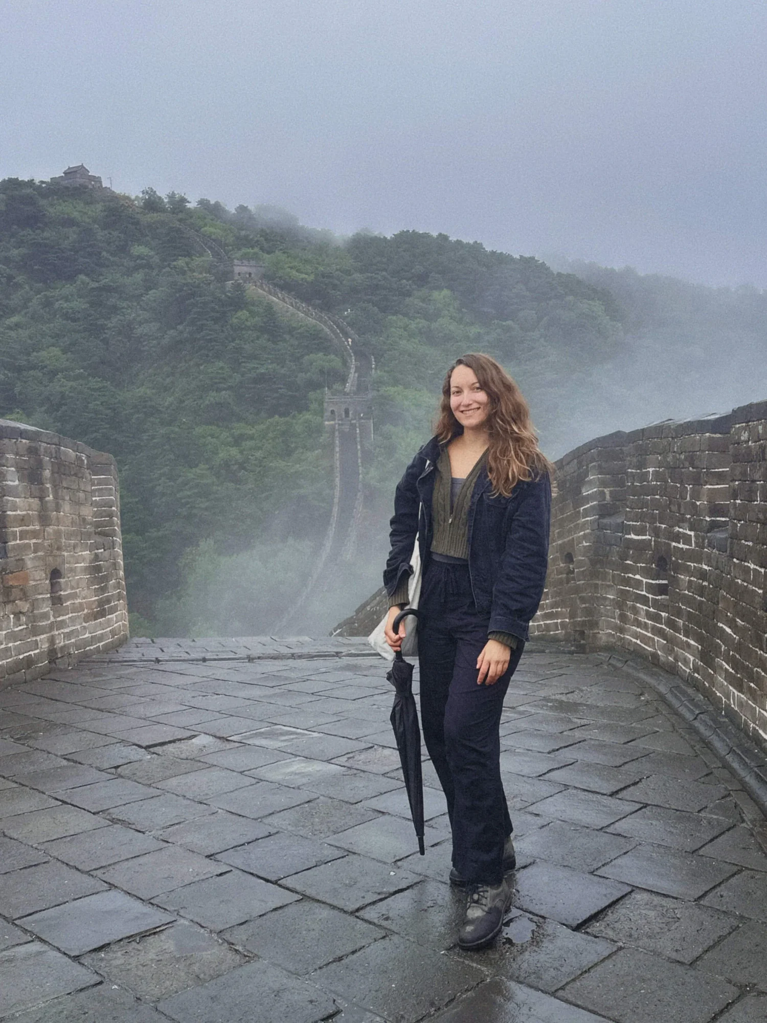 Travel writer Amy Suto standing on the Great Wall of China after rainfall during a Great Wall of China tour from Beijing. Mist rising from the mountains, empty walkways, and breathtaking views from this once-in-a-lifetime Great Wall of China trip.